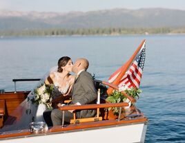 bride and groom kissing on the back of a boat with American flag