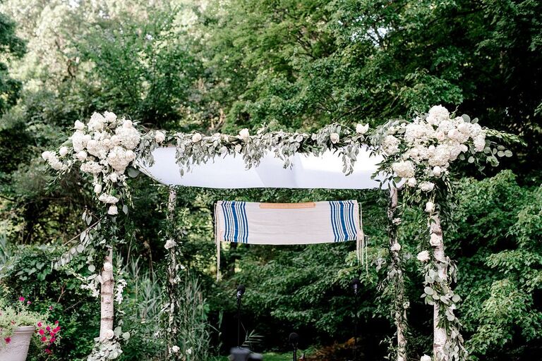 Floral chuppah with tallit suspended from the top.