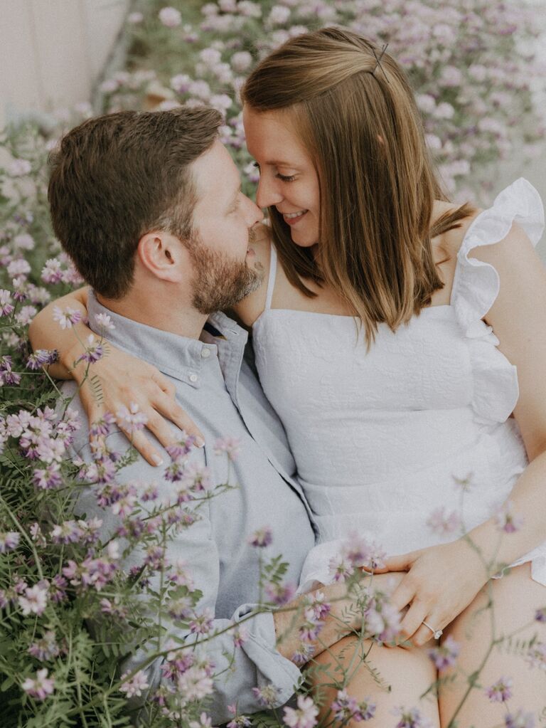 Couple surrounded by flowers for their summer engagement photo shoot. 