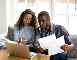 Couple sitting on a couch looking at a computer