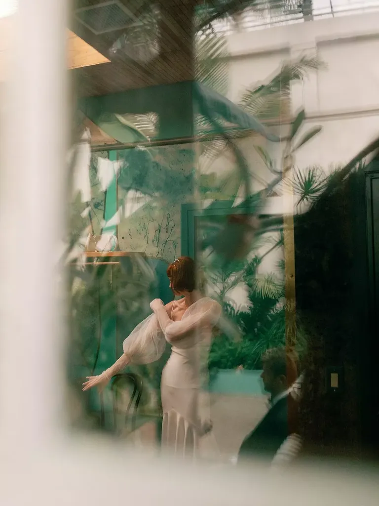 Artistic Film Through Window of Bride Putting on Detachable Sleeves Before Wedding