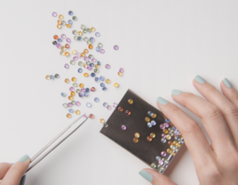 person's hand with loose gemstones