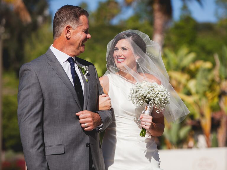 Bride in a veil and father outdoors for wedding pictures
