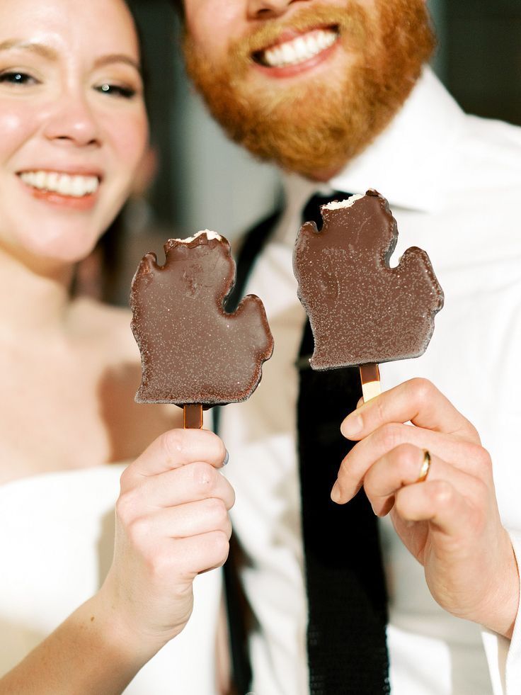 Couple holding chocolate-covered ice cream bars shaped like Michigan