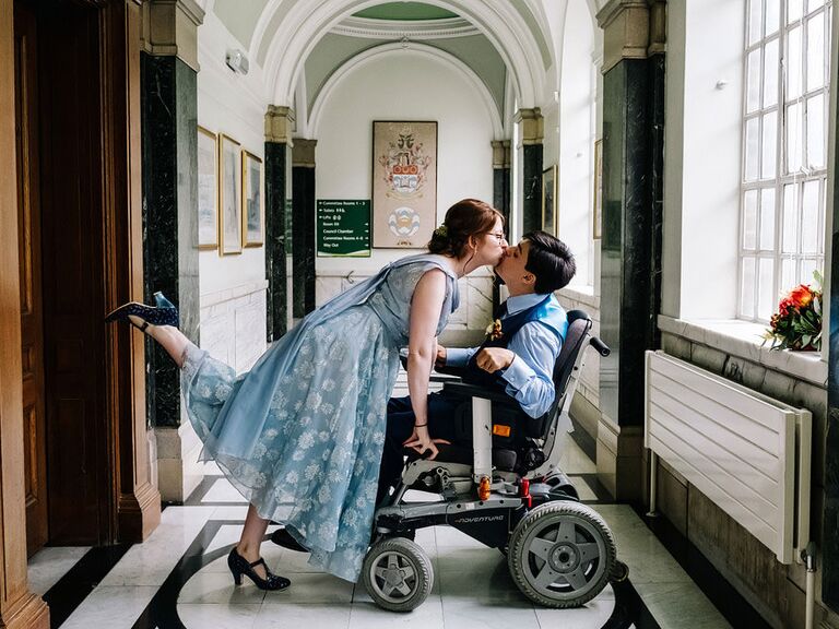 Bride in blue dress kissing groom with foot up