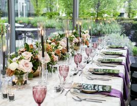 modern romantic wedding tablescape with low rose centerpieces, black taper candles, menu cards, purple water goblets and linen napkins