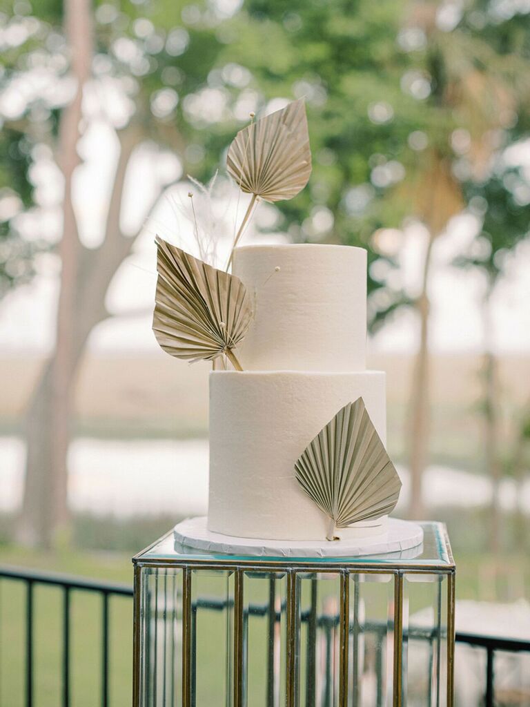 Trendy beach wedding cake with two white tiers and pressed gold palms