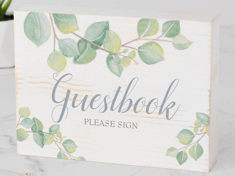 'Guestbook' in simple blue calligraphy with greenery graphics 