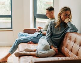 Frustrated couple sitting on couch at home