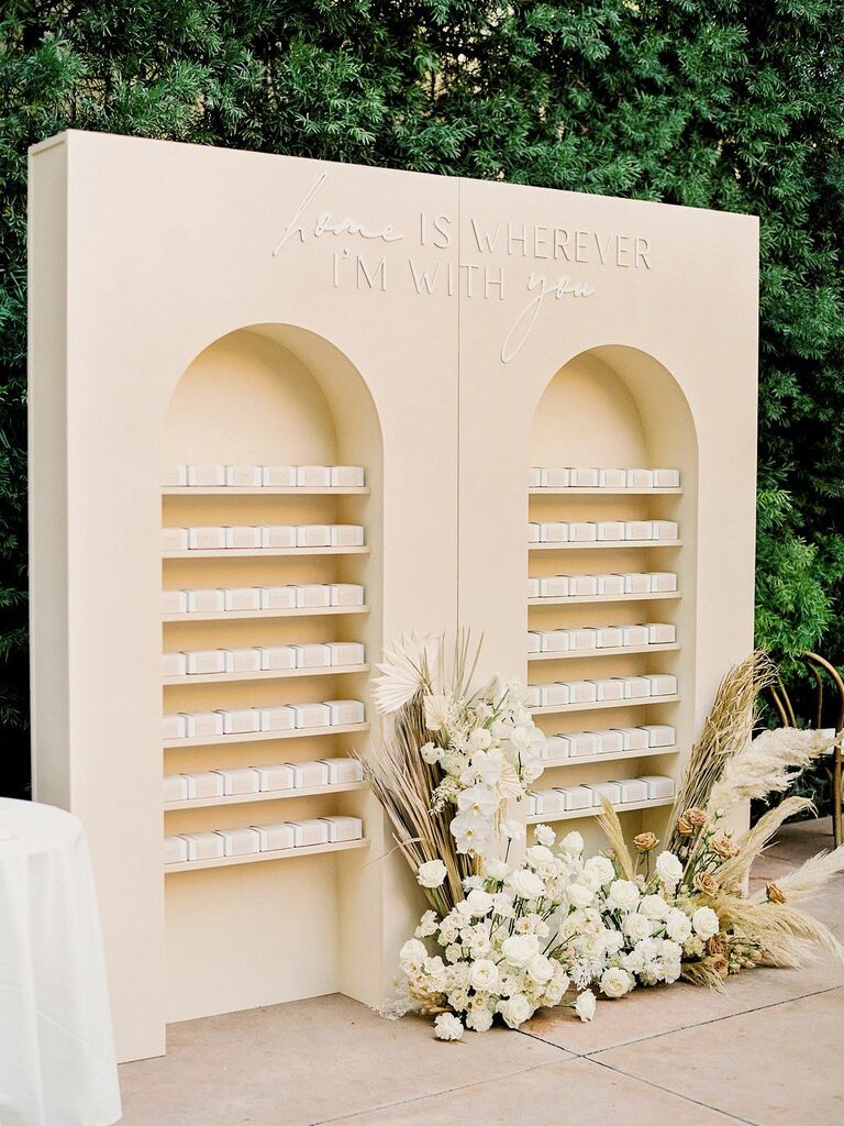 custom wedding favor display wall with arched shelves and laser cut quote that reads home is wherever i'm with you