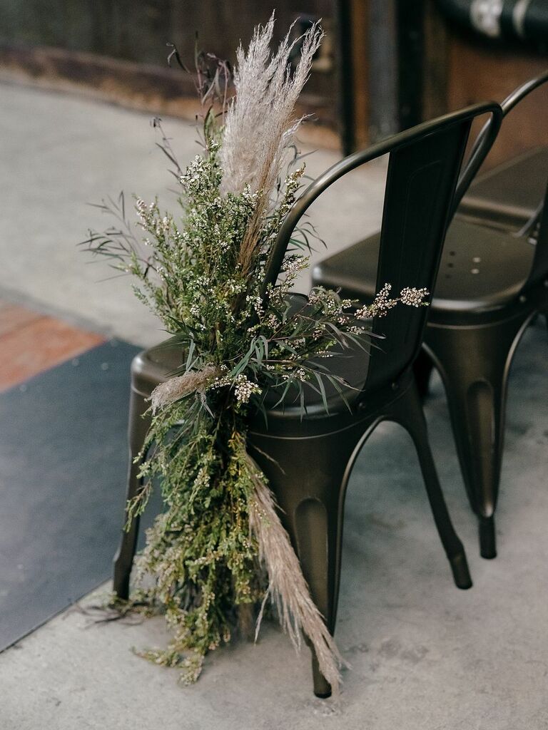 modern aisle marker for wedding with greenery and pampas grass on black metal marais chair