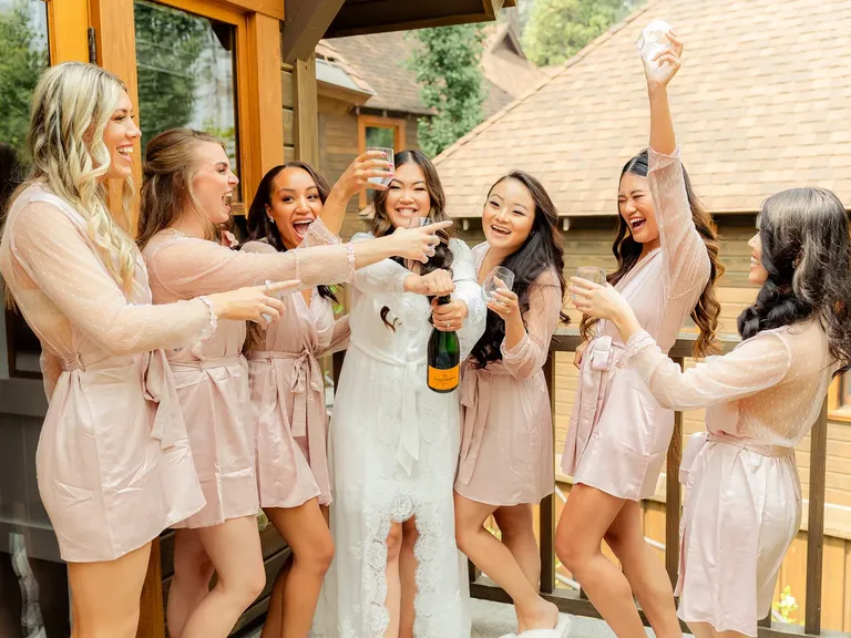 Bridesmaids and bride dancing and laughing with champagne
