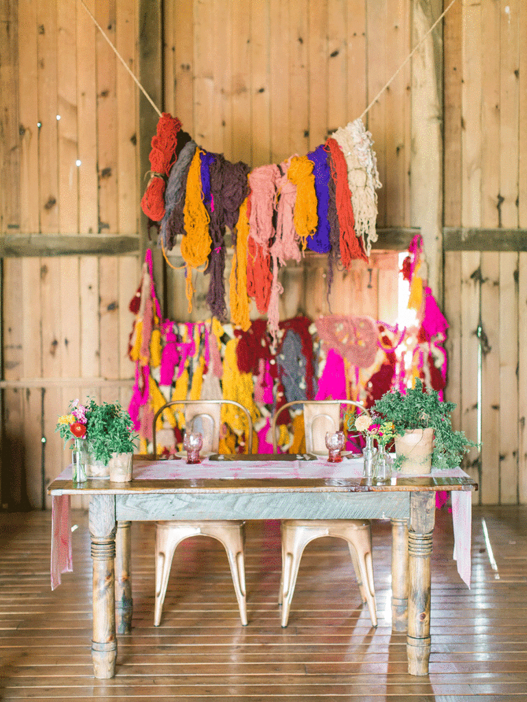 Colorful yarn backdrop at DIY bohemian wedding. 