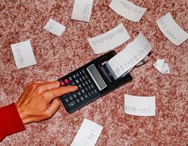 Man's hand using calculator to calculate registry completion discount