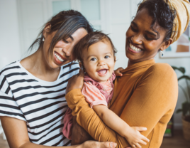 Married couple holding their baby and smiling