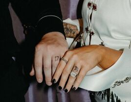 Couple with wedding ring tattoos holding hands