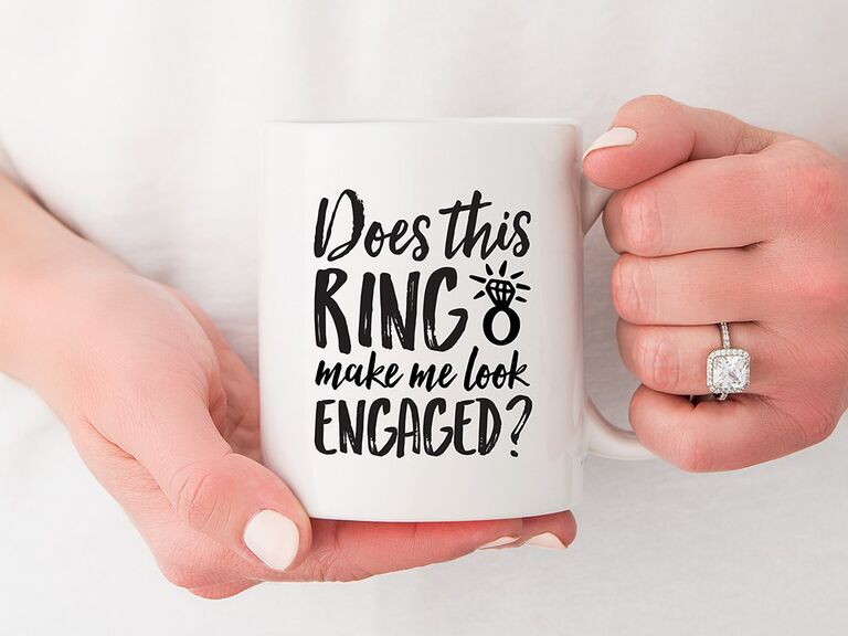 'Does this ring make me look engaged?' in black type with ring graphic on white mug