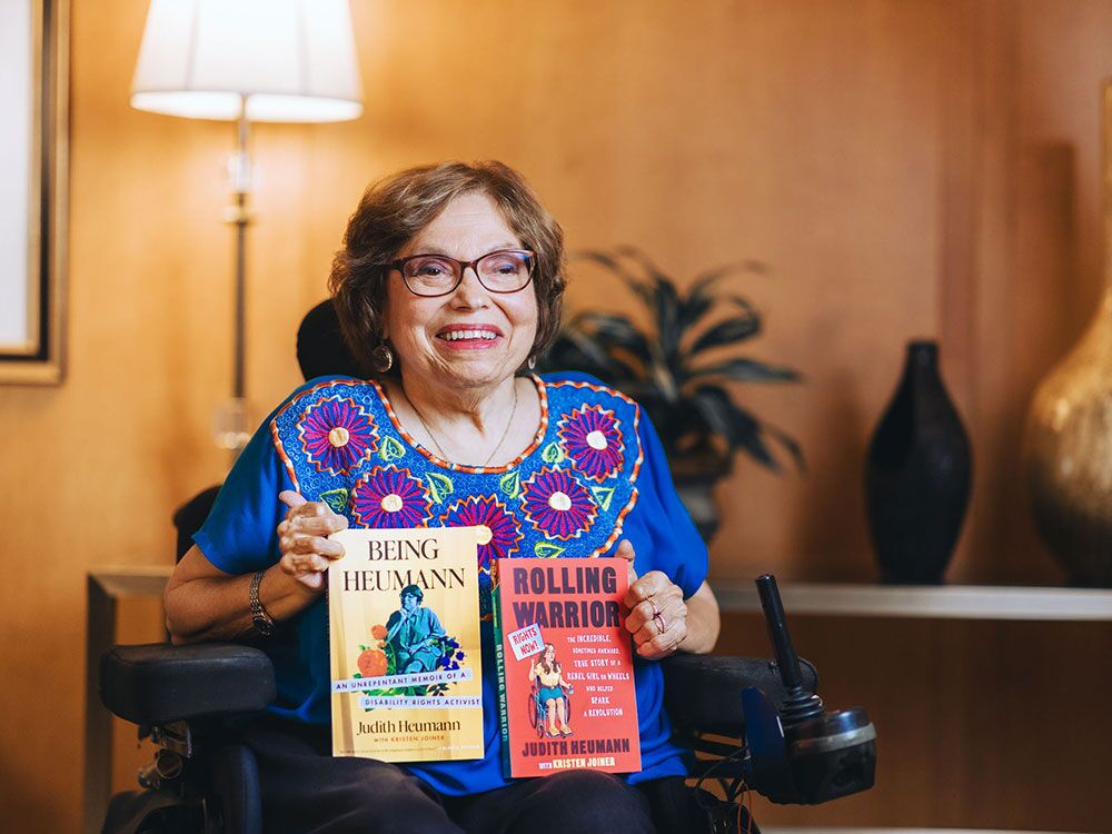 Author Judy Heumann holding her two books