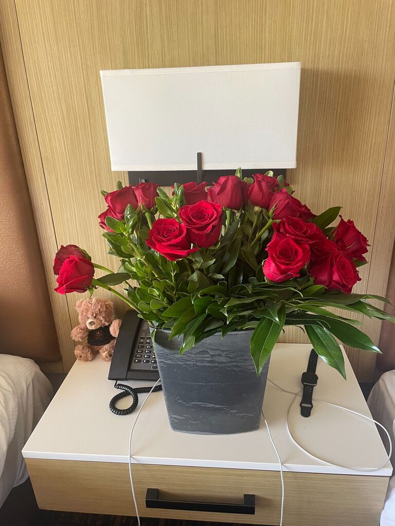 🚗🌹 Jeremy picked Danielle up for their first road trip, surprising her with the most beautiful red roses. Danielle felt like royalty 👑 as they arrived at the Desert Princess Country Club in Palm Springs, California. Jeremy, ever the considerate partner, carried all their luggage 🧳, making her think, “He's a keeper.” The amusing twist? They didn’t have a vase for the two dozen roses, so they had to improvise and use the hotel room trash can 🗑️. It was a moment of laughter and love, marking the start of many adventures together. 💕😊