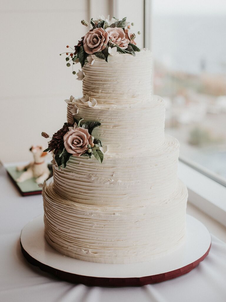 four tier wedding cake with rippled buttercream and pink sugar flowers