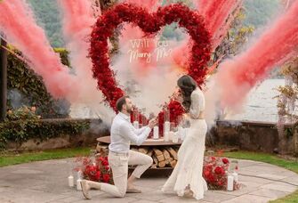 Man down on one knee in front of a romantic engagement display