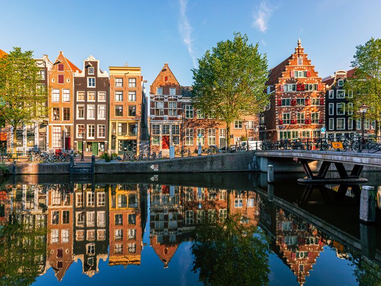 Old historic Dutch houses reflecting in the canal on a sunny day, Amsterdam, Netherlands