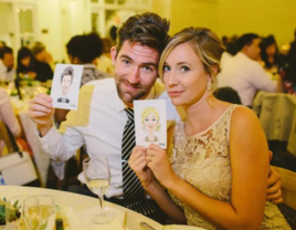 Bride and groom holding up caricatures by Cartoon.guru