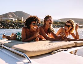 3 women laying out on beach and laughing