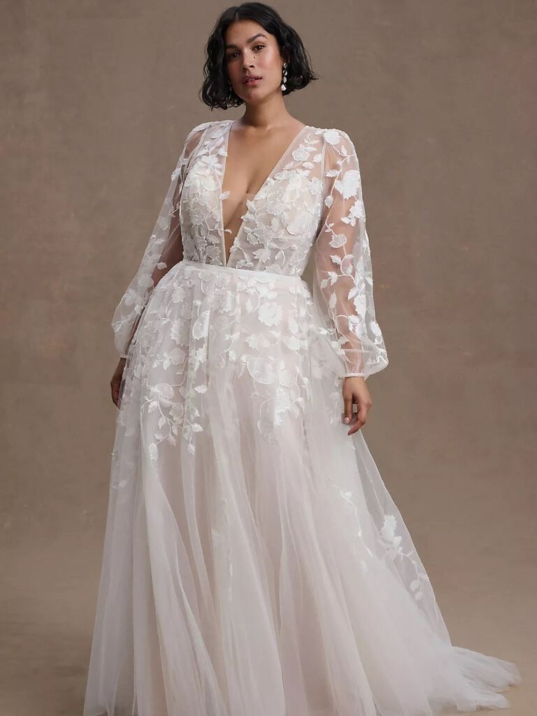 Model wears a long sleeved floral wedding dress, floral wedding dress trends 2023-2024. 