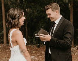 Smiling groom reads private vow to smiling bride.