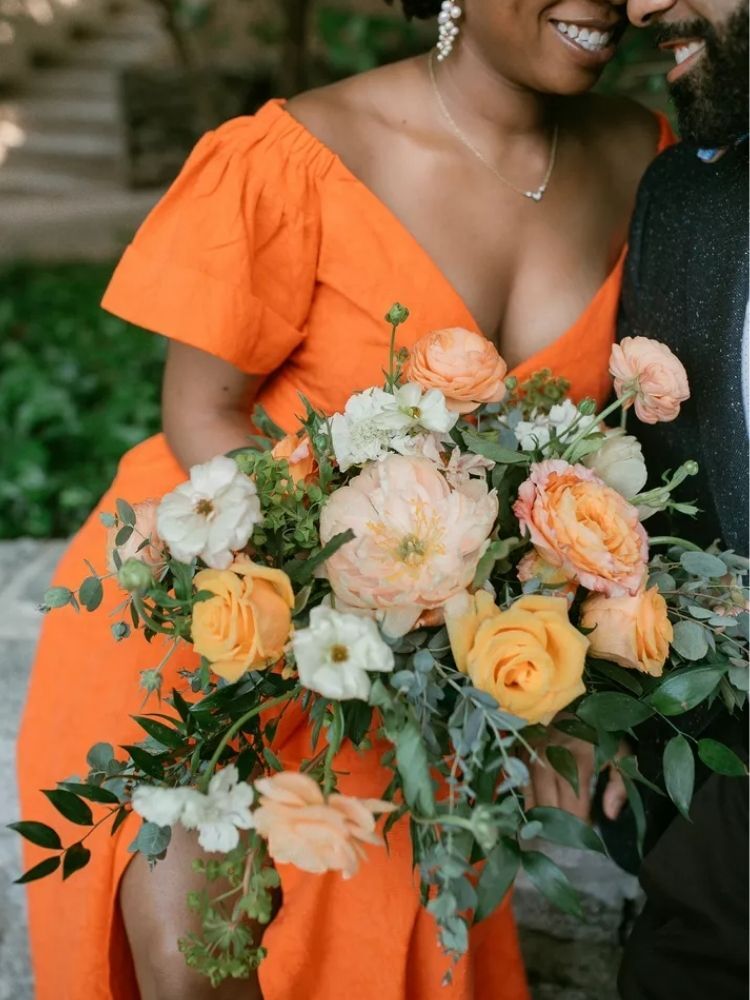 bride in orange dress holding orange rose bouquet
