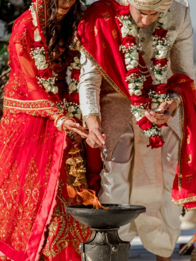 couple putting things in ceremonial fire during Indian wedding 