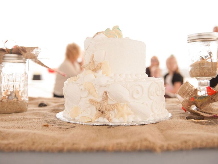 Two-tier beach wedding cake with white frosting and seashells