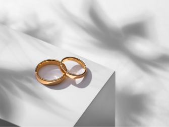 Wedding rings on a wooden box with shadows of leaves