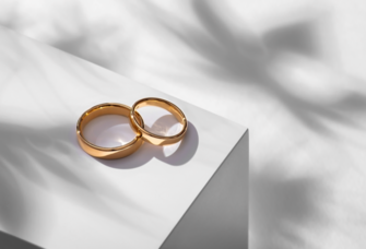 Wedding rings on a wooden box with shadows of leaves