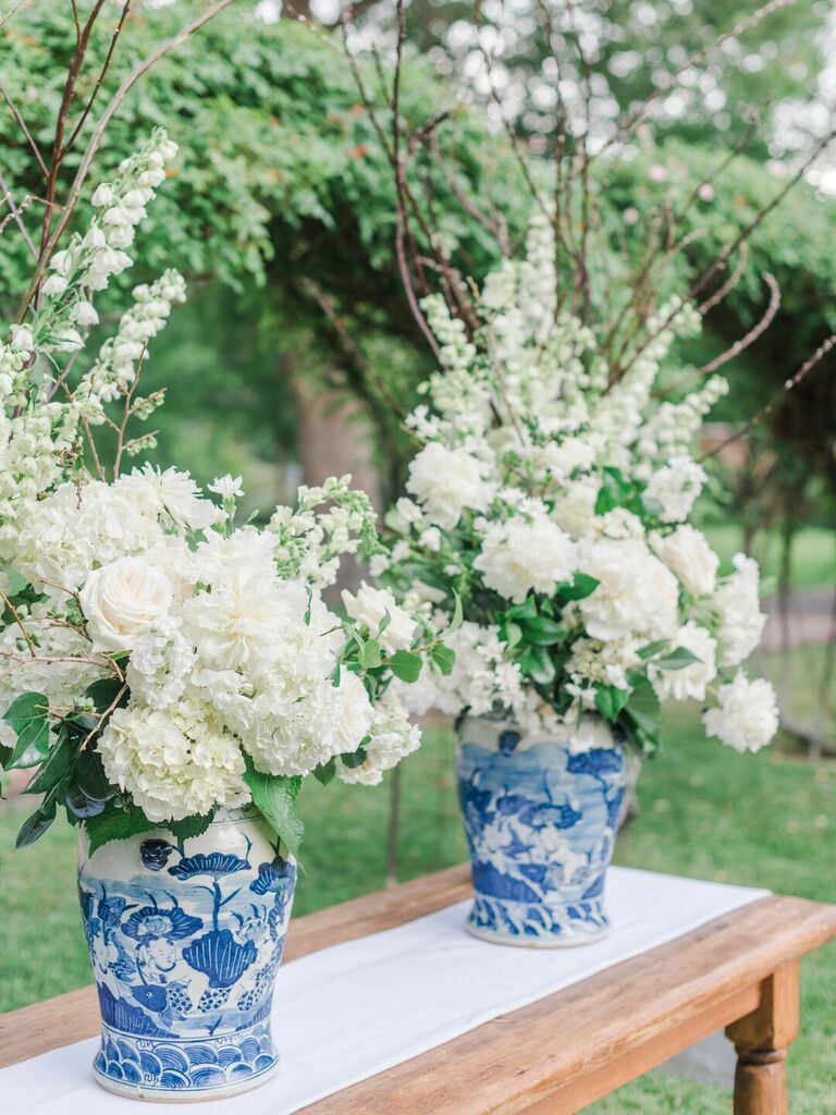 oversized blue and white chinoiserie vases filled with white hydrangeas, roses and curly willow branches