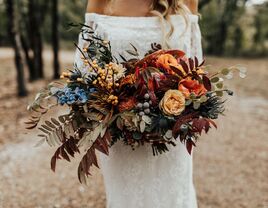 unique fall wedding bouquet with orange roses, greenery and red fall foliage