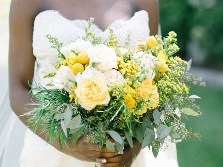 A bride holding a yellow bouquet of craspedia and goldenrod flowers