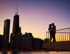 A couple kissing with the Chicago Skyline in the background during sunset.