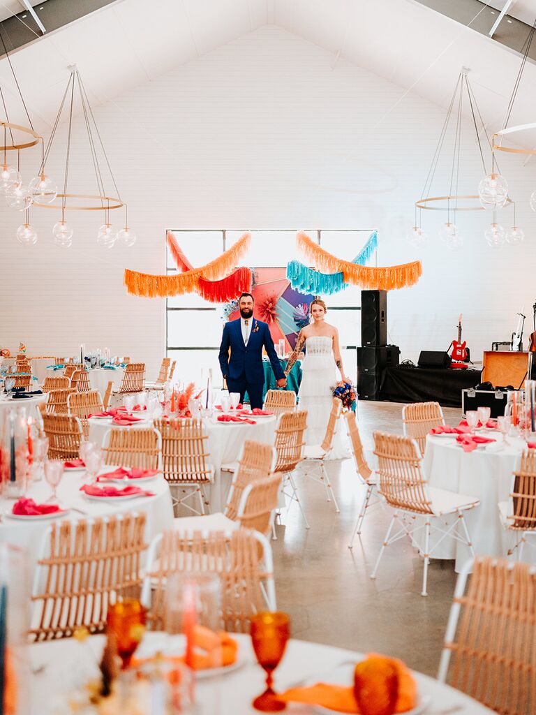 A couple hold hands across their reception space.