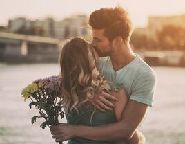 Woman and man embracing with flowers in the sunset