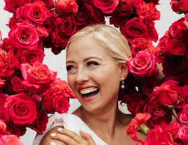 A bride smiles, surrounded by breathtaking pink floral arrangements.