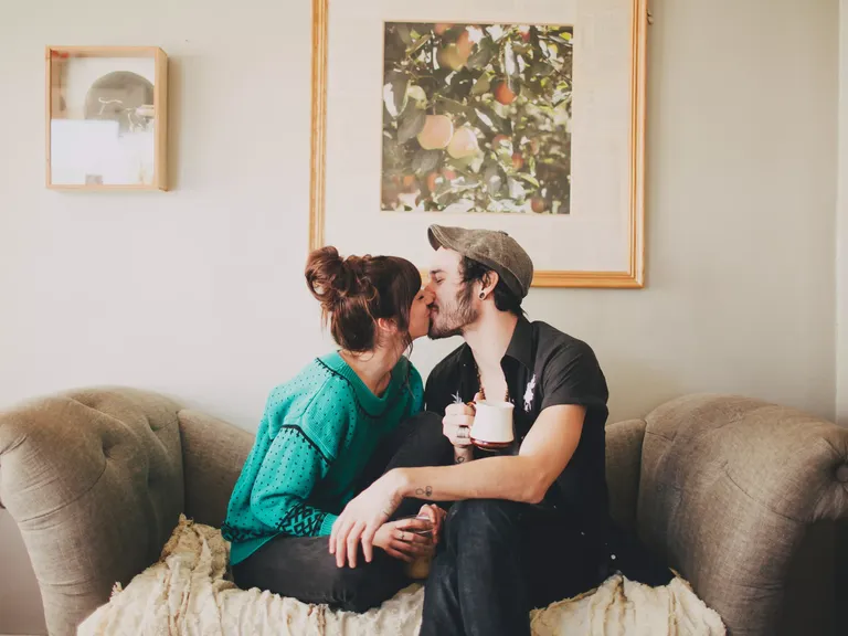 Couple kissing on couch after surprise at home engagement