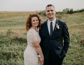 wedding couple poses with field backdrop