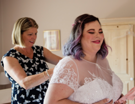 Mother-in-law zipping up bride's dress