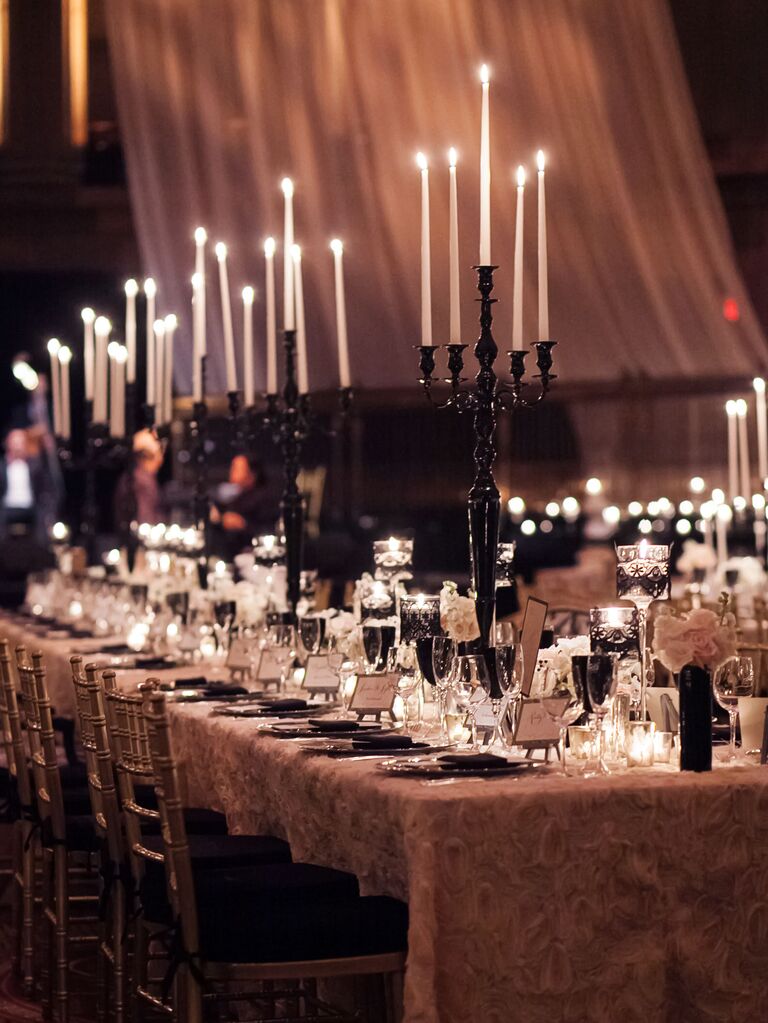long wedding reception table with white textured tablecloth and black candelabras with white taper candles
