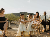 Toddler flower girls in white dresses walking down aisle at outdoor wedding