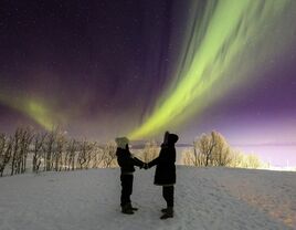 A couple watchs the aurora borealis (northern lights) near Björkliden Fjällby, Sweden