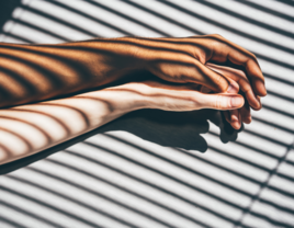 Couple holding hands in shadow of window shades