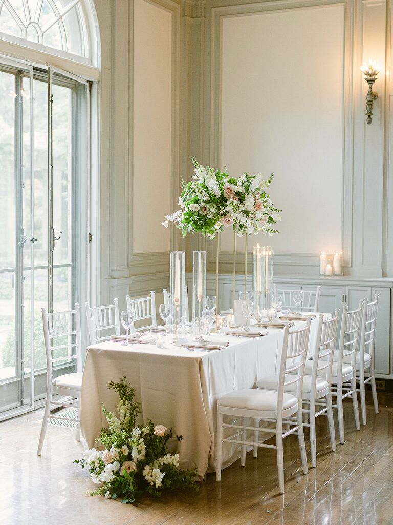 classic wedding reception table with tall centerpieces and white chiavari chairs
